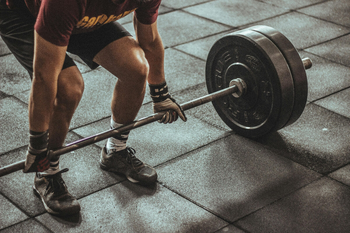 Person lifting a barbell on a tiled floor
