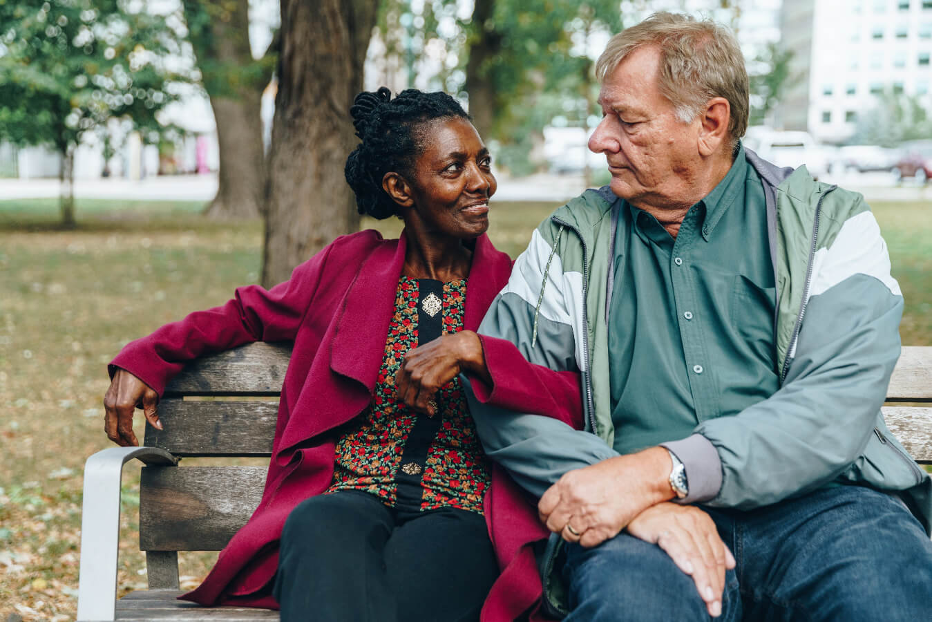 Two people sitting on a park bench, engaged in conversation.